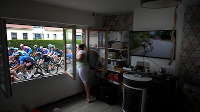 A woman cheers the riders from inside her home on Stage 4. AP