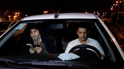 An Iranian woman reads the Quran as worshippers sit in their vehicles while taking part in a religious ceremony during Ramadan in a parking area of Tehran's Eram park in the Iranian capital. AFP