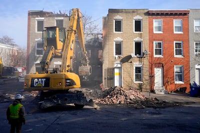 An excavator is used to pull debris off a building during efforts to retrieve the body of a deceased firefighter caught in the building's collapse. AP