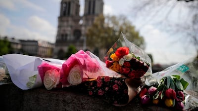 Flowers are laid on a bridge in front of the Notre-Dame Cathedral in Paris on April 17, after a fire caused major damage to the 850-year-old landmark. AFP
