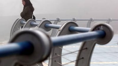 A woman takes in the view along the corniche on 18th street during heavy fog in Abu Dhabi on Monday.