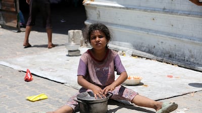 A girl sits as Palestinians gather to receive food cooked by a charity kitchen amid shortages of aid supplies in Khan Younis, the southern Gaza Strip. Reuters