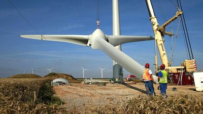 Workers lift a rotor hub on the tower part of an E-70 wind turbine during its installation at a wind farm in Meneslies. France will mobilise about €10 billion for a package of tax breaks, low-cost loans, and bonuses to boost investment in renewable energy. Benoit Tessier / Reuters