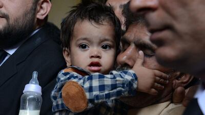 Nine month Pakistani toddler Mohammad Musa is held by his grandfather Muhammad Yasin, during a court hearing in Lahore on April 12. Arif Ali / AFP Photo