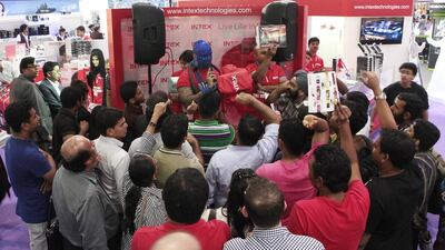 Loy Machedo, covered in sparkling blue glitter paint, leads the bidding of electronic devices at Intex Technologies as enthusiastic shoppers bid for items from Dh1 at Gitex Shoppers 2013. Jeffrey E Biteng / The National