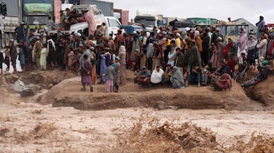 People in Afghanistan wait to cross a flooded road in Herat province on Thursday. Photo: AFP