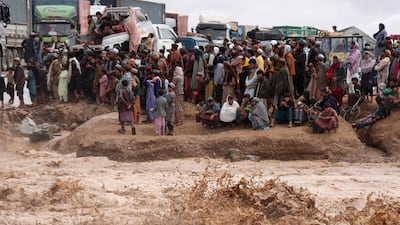 People in Afghanistan wait to cross a flooded road in Herat province on Thursday. Photo: AFP
