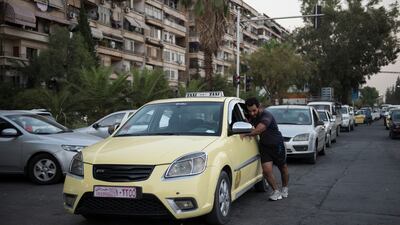 A Syrian taxi driver pushes his car to the petrol station to refuel. Hasan Belal for The National