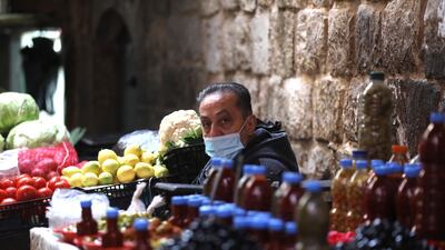 A Palestinian vendor wears a face mask while waiting for customers in Nablus, West Bank. EPA