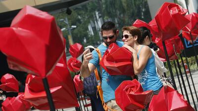 Foreign tourists take a selfie with red roses on display ahead of Valentines Day outside a shopping mall in Bangkok, Thailand (EPA/NARONG SANGNAK)