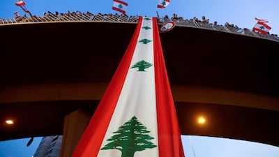 Demonstrators stand on a bridge decorated with a national flag during an anti-government protest along a highway in Jal El Dib, Lebanon. Reuters