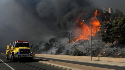 A fire crew passes a burning home during a wind-driven wildfire in Ventura, California. Mike Blake / Reuters