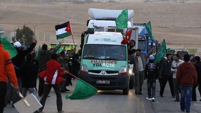Jordanians wave to the aid convoy with flags and throw flowers near the border between Jordan and Syria yesterday