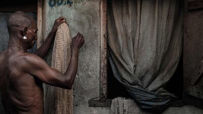 A fisherman repairs a net in front of his house at Egede informal settlement in Port Harcourt, Nigeria. AFP