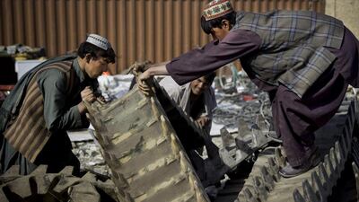 Afghan scrap dealers try to load giant rubber treads of a US tank received from the departing military as junk in Kandahar, southern Afghanistan. Anja Niedringhaus / AP