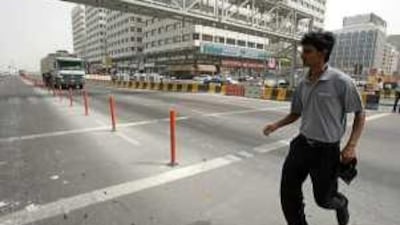 A pedestrian crosses the road in front of a lorry at the entrance to Abu Dhabi Mall.