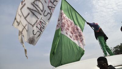 A protester raises the Nigerian flag alongside an EndSARS flag. AFP