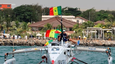 Patrick Bol, Dutch skipper of the Row4ocean rowing trimaran holds a Senegalese flag as his team leaves Dakar to cross the Atlantic on December 14, 2018. AFP