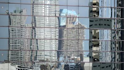 Towers are reflected on the windows of an office building in Tokyo. A strong yen is hitting profits for Japanese companies who mainly operate overseas. Franck Robichon/EPA