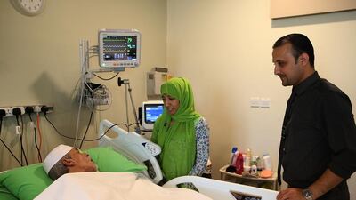 Salma Al Ghaithi visits her father at CMRC, with nurse manager Abdullah Abu Mustafa looking on. Ravindranath K / The National