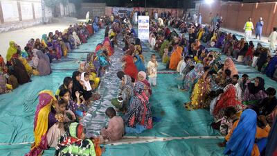 Flood-affected people eat food distributed by Al Mahmood Social Welfare Association in Larkana. EPA