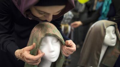 A Russian Muslim woman ties an Islamic head scarf onto the head of a mannequin during a celebration of the World Hijab Day in Moscow (AP Photo/Alexander Zemlianichenko)