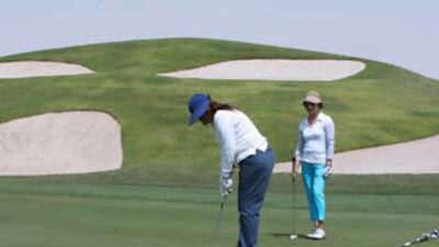A panoramic view of the green on the fourth hole of the Montgomerie Golf club with the sprinkling of bunkers behind it.