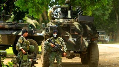 This photo taken on September 5, 2016, Philippine soldiers standing guard next to an Armored Personnel Carrier (APC), inside a military camp in Jolo, Sulu province, in southern island of Mindanao, as they prepare for an operation against the extremist Abu Sayyaf group. - Philippine President Rodrigo Duterte has vowed to cannibalise and "devour" Abu Sayyaf Islamist militants who allegedly bombed his home city last weekend, killing at least 14 people and leaving dozens injured. (Photo by MARK NAVALES / AFP)