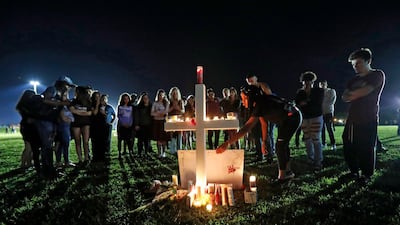 A woman places a poster of shooting victim Meadow Pollack, at one of seventeen crosses, after a candlelight vigil for the victims of the Parkland shooting. AP