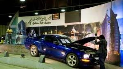One of the bidders inspects a Ford Mustang during the car auction at the Golden Bell Auctions pavilion in the Auto Market of Ras Al Khor in Dubai.
