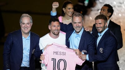 Lionel Messi holds his new Inter Miami team jersey as he poses with team co-owners Jorge Mas, left, Jose Mas and David Beckham. AP
