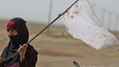 An Iraqi woman, displaced from the outskirts of ISIL stronghold Hawija, about 65 kilometres east of the northern city of Kirkuk, raises a white flag while travelling with family members and a donkey-cart on the road outside the town on October 3, 2017. Ahmad Al Rubaye / AFP