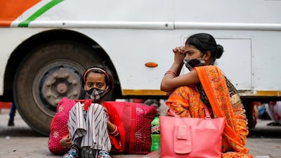 A migrant worker's family sits next to a bus at a bus station, as they wait to return to their village, after Delhi government ordered a six-day lockdown to limit the spread of the coronavirus disease, in Ghaziabad on the outskirts of New Delhi, India. Reuters