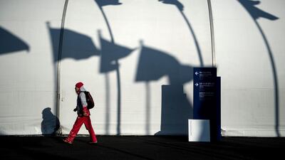 A volunteer walks past shadows of competing nation's flags in the Gangneung Olympic Village as preparations for the Pyeongchang 2018 Winter Olympic Games continue. Brendan Smialowski / AFP