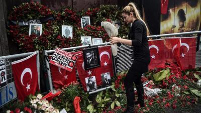 A woman lays flowers by a makeshift memorial in front of the Reina nightclub in Istanbul, a day after Turkish police arrested the suspected attacker. Ozan Kose / AFP