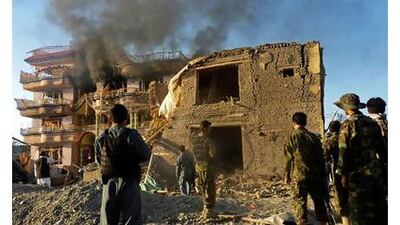 Afghan security force members stand outside a US aid compound in Kunduz, northern Afghanistan, on Friday, July 2, 2010 after it was stormed by militants wearing suicide vests.