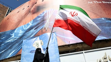 A woman holds Iran's national flag in front of a huge anti-US billboard in Tehran, Iran. EPA