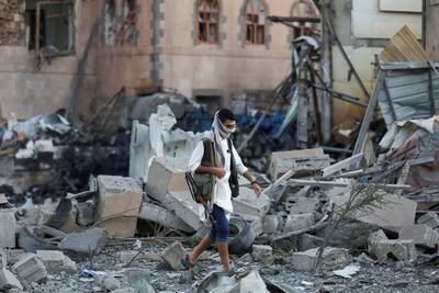 An armed man walks at the site of US strikes in Sanaa. Reuters