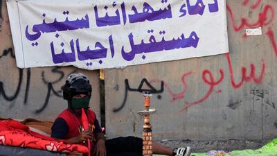 A protester smokes a shisha as he sits next to a banner reading in Arabic: 'The blood of our martyrs, will build the future of our generations' during a protest. EPA
