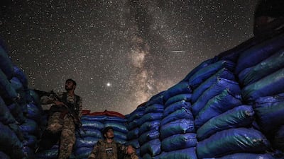 This long-exposure picture taken shows the Milky Way galaxy rising in the sky above Syrian fighters of the Turkish-backed National Front for Liberation group while on watch duty between sandbags in the town of Taftanaz along the frontlines in the country's rebel-held northwestern Idlib province. AFP