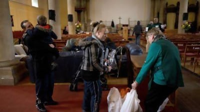 A volunteer, right, gives bags of groceries to a family at a food bank in St Luke's Church in West Norwood, London. More people are struggling to feed themselves as austerity measures hit the poor.