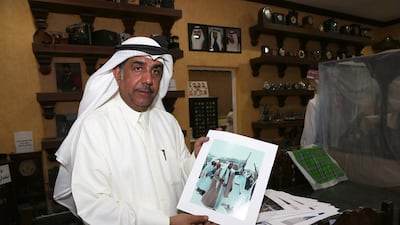 Jasim Al Ali holds the old picture of Sheikh Zayed he has as part of his expansive antiques collection at his home in Sharjah. Pawan Singh / The National