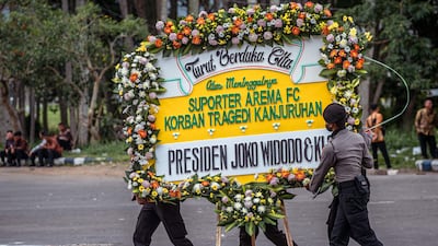 Police carry a wreath from Indonesia's President Joko Widodo at the Kanjuruhan stadium in Malang on October 5. AFP