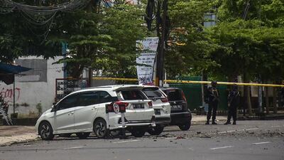 Police stand guard next to damaged vehicles after an explosion outside a church in Makassar. AFP
