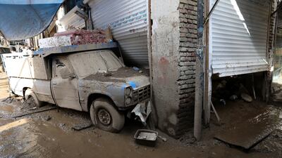 A vehicle and shop covered in mud after the flooding. AP Photo