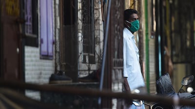 A man wearing facemask stands outside his house in the Dharavi slum, Mumbai. AFP