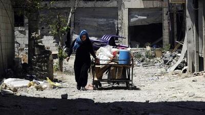 A woman pushes a cart carrying belongings recovered from her home in the Al Hamidiyeh neighbourhood. Omar Sanadiki/Reuters