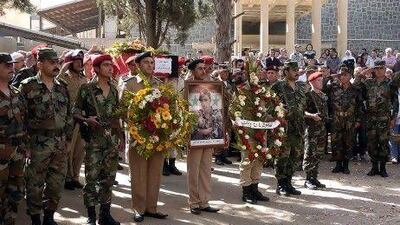 A handout photo released by the official Syrian Arab News Agency SANA shows Syrian policemen holding wreaths and carrying coffins of their comrades during a funeral procession in southern Syria on Friday.