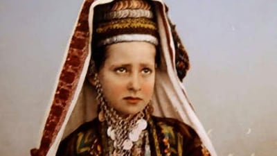 A Saudi bride poses in a heavily embellished wedding outfit, complete with coins.