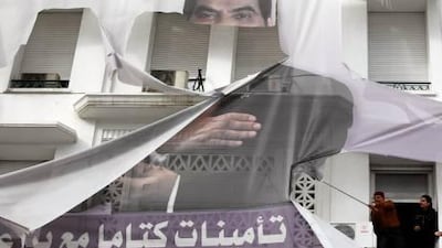 Two men try to remove a torn photo of former Tunisian president Zine El Abidine Ben Ali in the centre of Tunis.